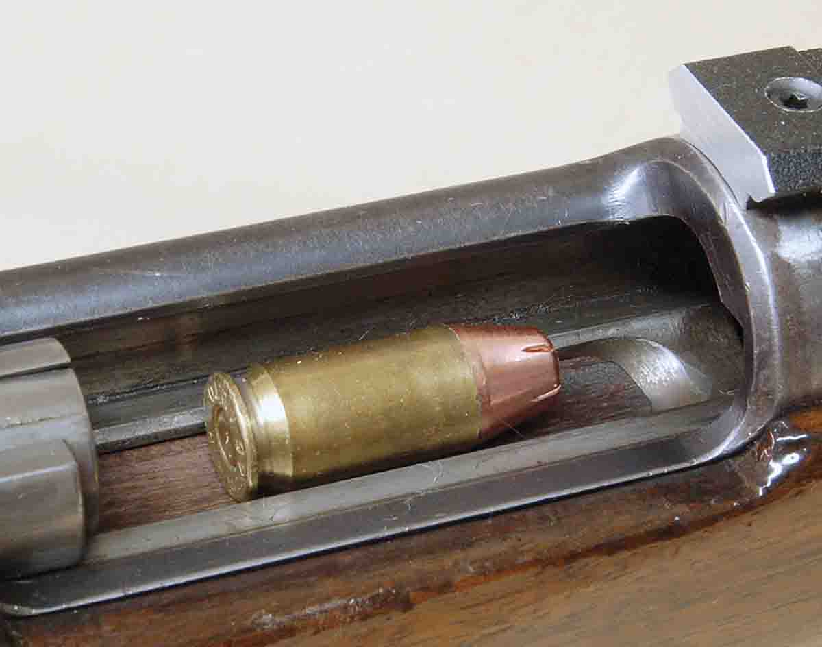 An open action with a cartridge lying on a wooden magazine filler. It feeds most bullet shapes perfectly, like this Hornady XTP.